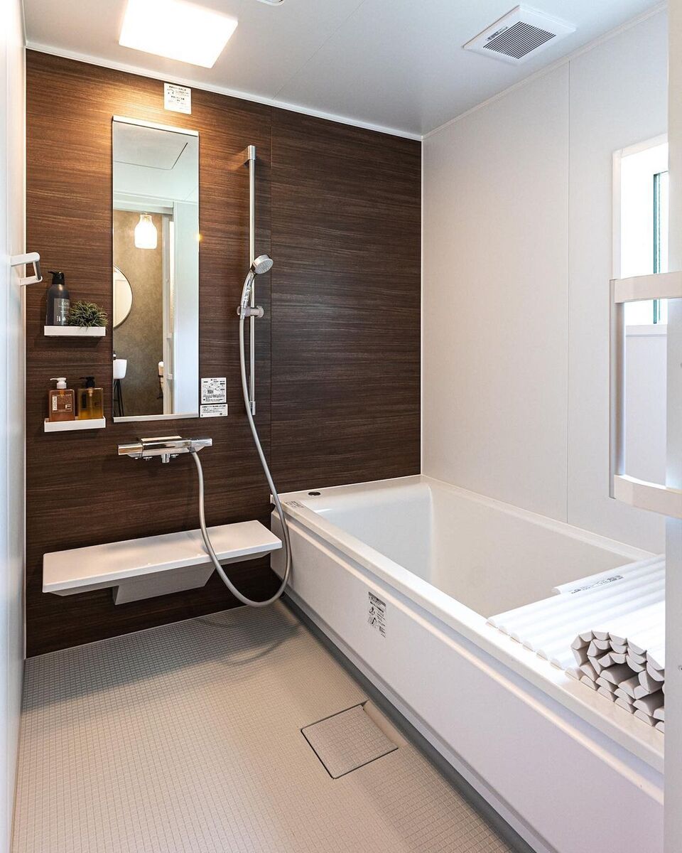 白を基調とした清潔感あふれるバスルームは、木目調のパネルがおしゃれなアクセントに！