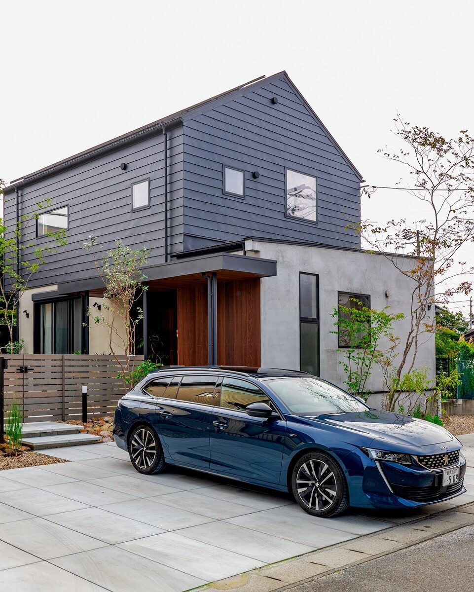 コンクリートと黒のガルバリウム鋼板、玄関アプローチは木目の美しいレッドシダー張りと、異素材の組み合わせを楽しんだ三角屋根のおしゃれな外観の家。モノトーンの外壁にはグリーンの植栽で彩りをプラス✨