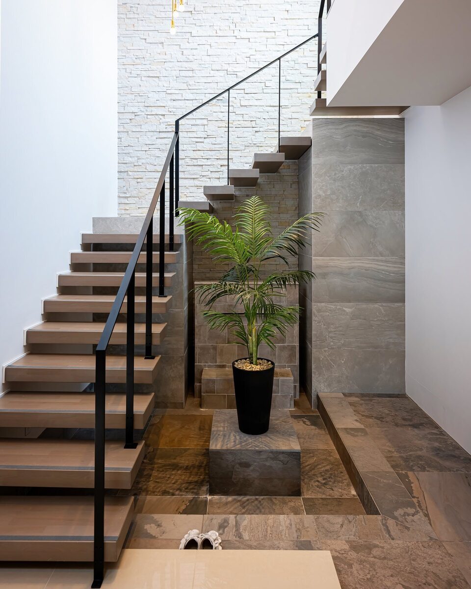 木×アイアンのスタイリッシュなスケルトン階段は、踏み板を厚くし、床や壁に石素材を加え、アースカラーでまとめることで、ラグジュアリーで重厚感のある落ち着いた空間に