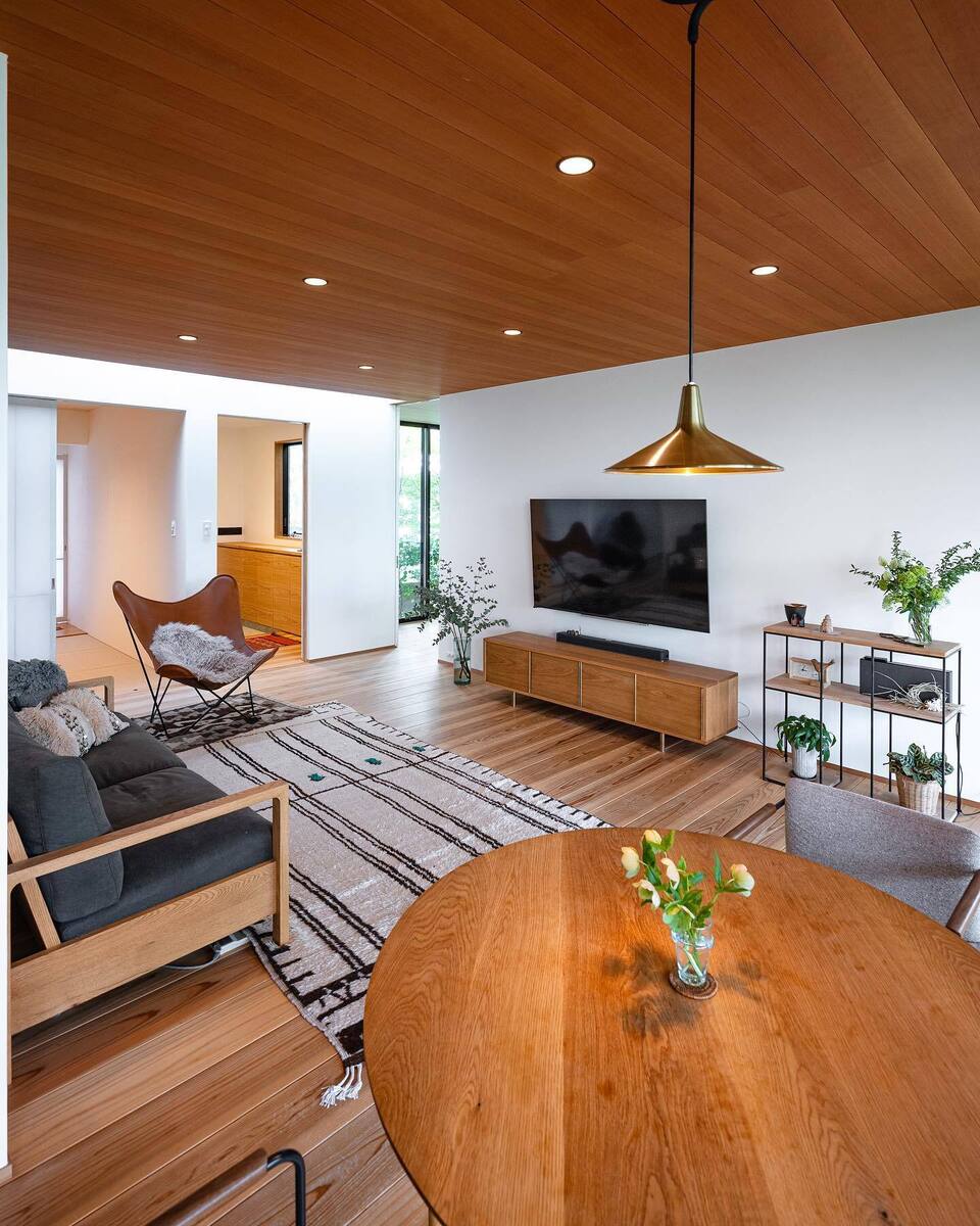 杉の無垢板を使用したフローリングは、あえて色味を合わせず、交互に濃淡をつけておしゃれにデザイン。テーブルやテレビ台等、家具もナチュラルブラウンで揃えた温かみのあるリビングルーム