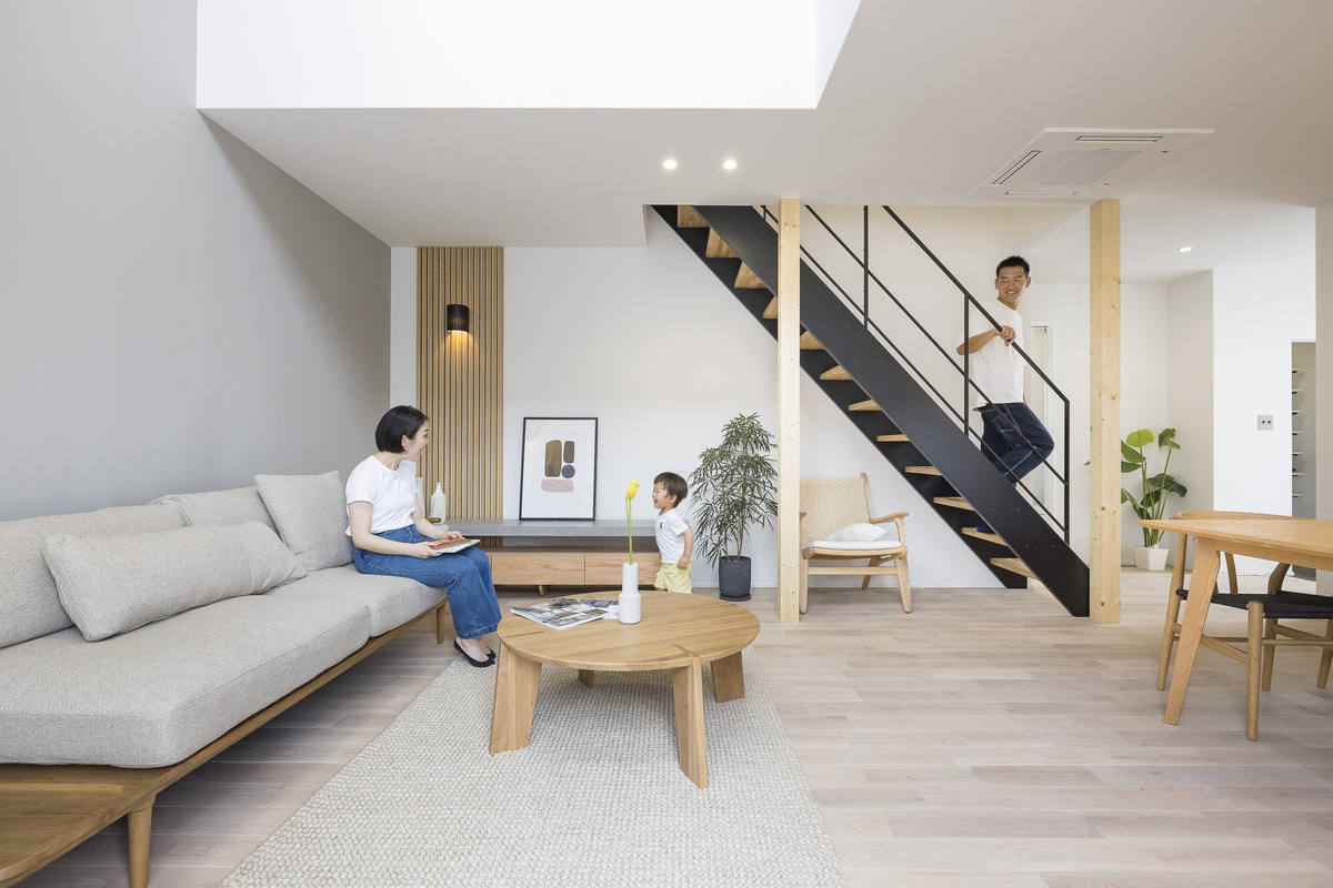 白を基調とした明るい空間に白いフローリングやくすみグレーのアクセントクロスを加えた北欧テイストのリビングルーム。スケルトン階段のアイアン手すりが引き締めカラーに。