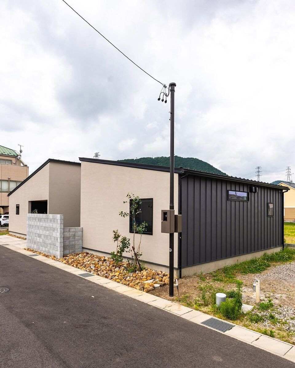 シンプルなフォルムの平屋のお家は、ナチュラルなベージュカラーの外壁にブラックのガルバリウムの部分使いでシックな印象に！植栽のグリーンは外観に彩りを与えつつ、窓の前に植えることで室内から緑を楽しんだり外部の視線を遮ったりと良いことづくし◎