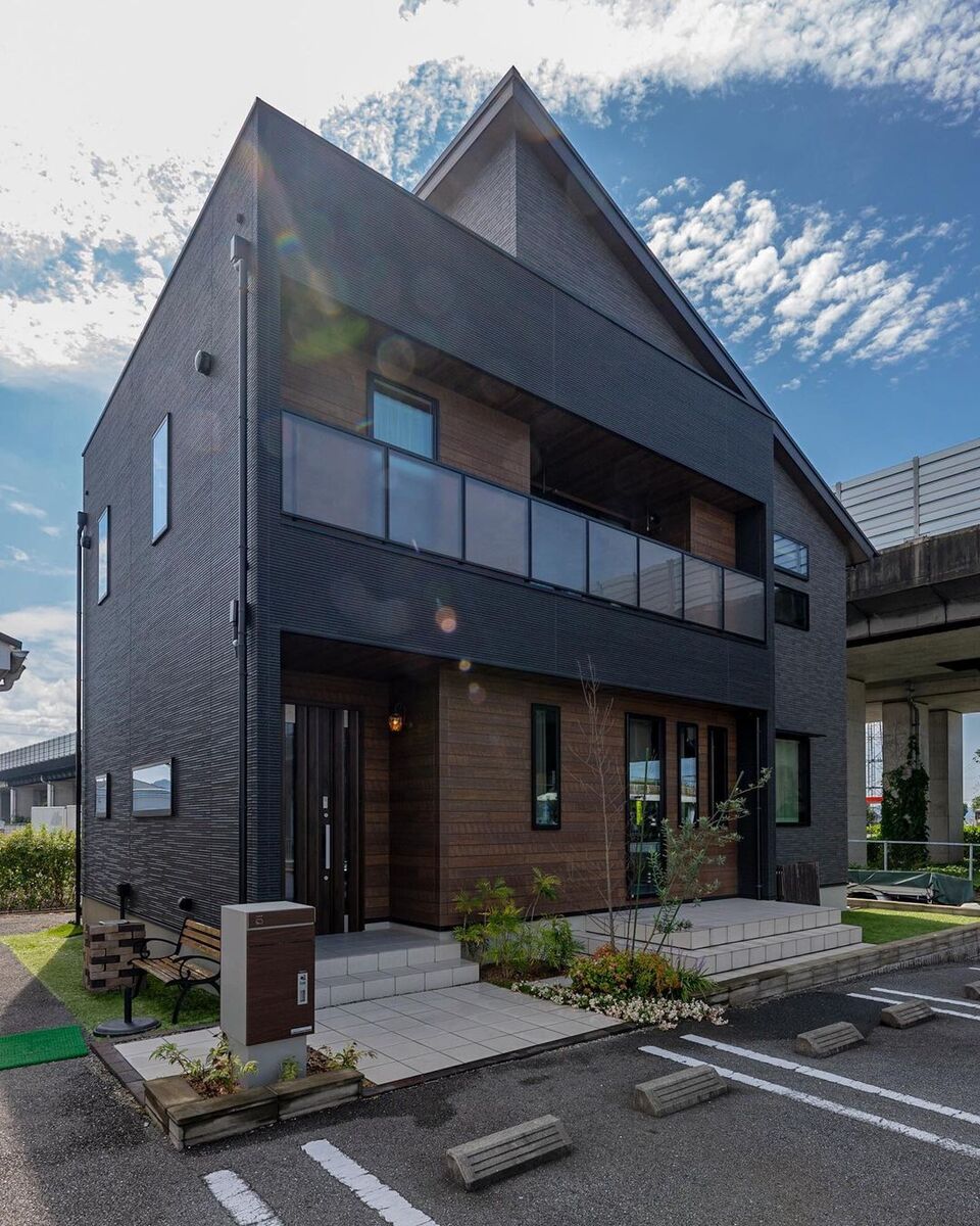 紺色×グレーの外壁に、キューブ型と片流れ屋根のスタイリッシュなフォルムの組み合わせがクールでお洒落な外観の家。部分的にあしらわれた木目や、玄関ポーチ周りの白いタイルと植栽で、優しい印象をプラスしています。