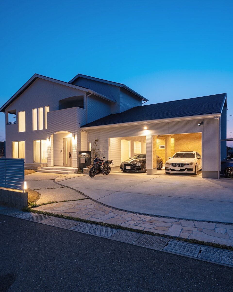 天然石を敷き詰めたおしゃれな玄関アプローチを進んだ先には、白い壁にネイビーの屋根、ビルトインガレージ付きの素敵なお家。玄関ポーチのアーチと玄関アプローチの曲線で優しい雰囲気を加えて。
